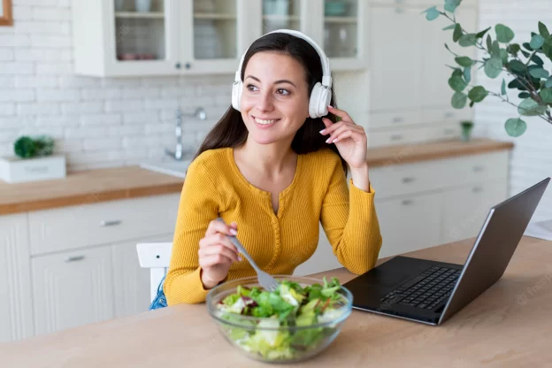 Какво значение има музиката по време на хранене? - woman listening music while eating salad 23 2148238892