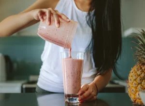 Здравословните навици удължават живота - woman pouring smoothie from blender into glass